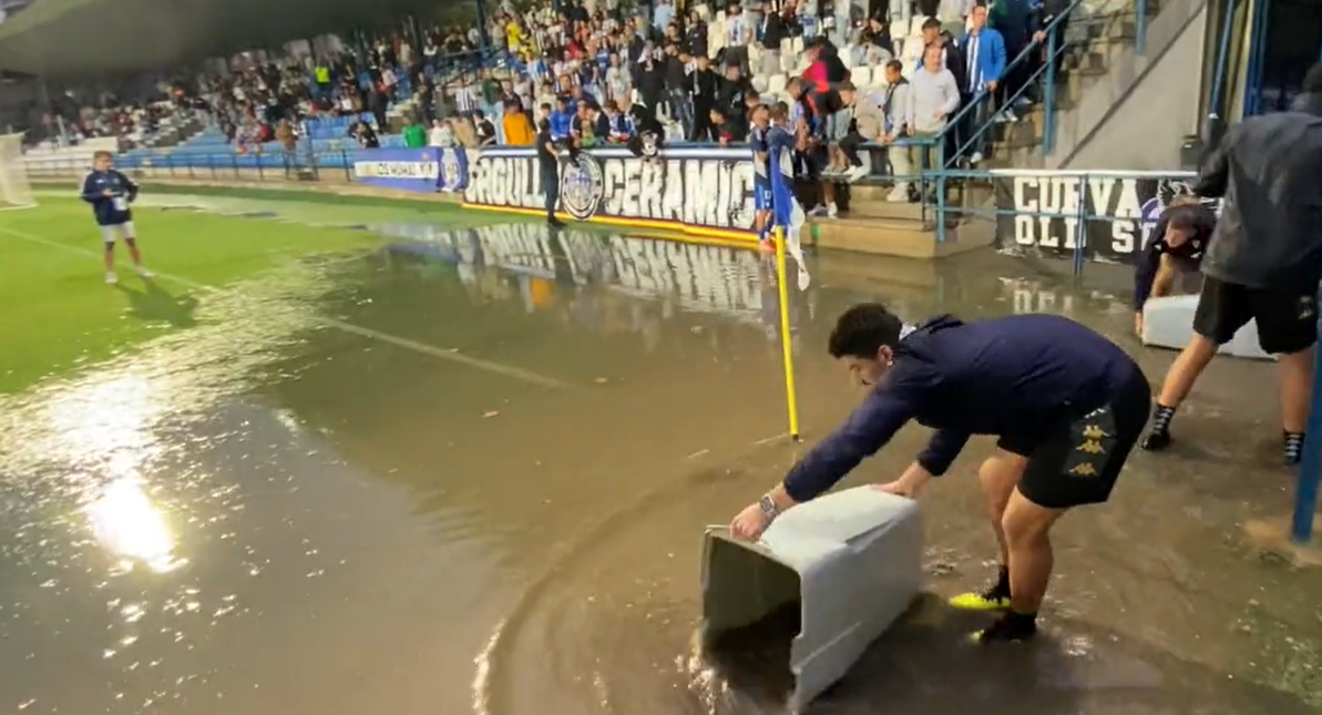 Jugadores del C.F. Villanovense achican agua antes de un partido debido a las inundaciones del campo