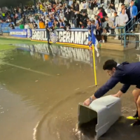 Jugadores del C.F. Villanovense achican agua a pie de campo antes de un partido